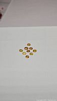 Top-down view of 9 oval-shaped yellow and orange sapphires arranged on white background.