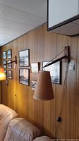 Lamp mounted on wood-paneled wall above sofa and artwork