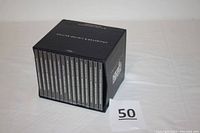 Box set containing all 15 CD cases upright, showing the uniform black color with white text on the spine.