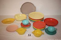 Photo of full set with various Melmac plates, bowls, cups, and serving pieces in multiple colors including yellow, red, turquoise blue, cream, tan, and gray.