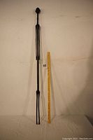 Full length image of the carved wooden staff next to a measuring stick showing a height of approximately 5 feet.