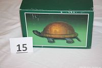 Box containing the turtle lamp with a picture of the turtle lamp on the box showing amber glass shell and metal turtle body.