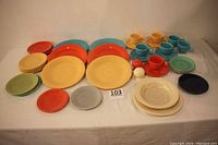 Full view of all dishes, displaying the range of plate sizes, teacups, saucers, salt and pepper shakers, and soup bowl arranged in colorful groups with white table background.
