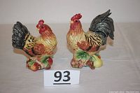 Pair of Fitz and Floyd Classics ceramic rooster and hen salt and pepper shakers photographed from the front and side views.