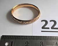 Top view of gold filled hinged bracelet showing overall band and ruler for size reference