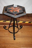 Front view of hexagonal table showing concrete top with embedded glass flower decoration and steel base with curled feet.
