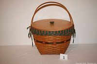 Front view of the woven Longaberger basket with lid on showing two handles, lid closed, and cloth liner visible around top edge.