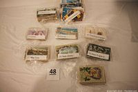 Bundles of postcards arranged in shrink wrap labeled by category including Comic, Florida, Thanksgiving Day, New York, New Jersey, New England, and mixed U.S.