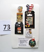 Seven Disney trading pins on display card showing various designs including Liberty Square, Mickey Mouse silhouette with flag, Adventures of Mickey Mouse pin, Walt Disney pin, Walt Disney World pin, and Aquarius pin