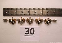 Front view of the silver grape cluster bracelet with gold tone leaves, measured against a ruler showing its length of about 7.25 inches.