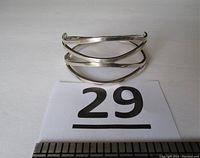 Front view of the open design sterling silver bracelet with three curved bands crossing, showing the shape and width.