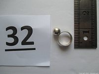 Top-down photo showing ring alongside a ruler for size reference and lot number.