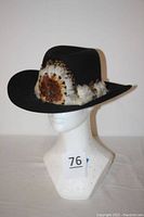 Front angled view of the black Stetson western hat with feather trim on mannequin head showing overall shape and feather band detail.