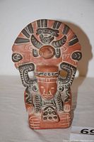 Front close-up of statue showing carved facial features and detailed headdress with painted patterns