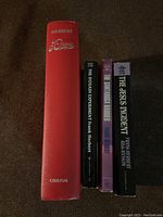 Photo showing the red hardcover edition of Dune by Frank Herbert with visible wear and spine text faded, alongside four Frank Herbert paperback books: The Dosadi Experiment, The Santaroga Barrier, Bill Ransom, and The Jesus Incident.