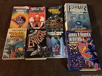 Top-down view of eight James P. Hogan sci-fi books laid out on a carpet, showing front covers and dust jackets.