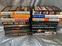 16 first edition books by Kathy Reichs stacked with front covers and spines visible, showing titles and author's name.