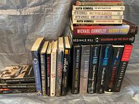 Photo showing a collection of mystery books stacked with spines visible featuring titles by Ruth Rendell, Reginald Hill, Michael Connelly, and Donna Leon