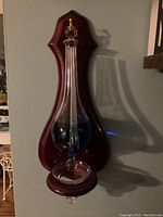 Storm glass barometer mounted on reddish-brown polished wood plaque, viewed from the front.