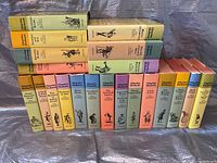 Full view of the 20 hardcover Charles Dickens books standing in two rows with colorful dust jackets on a silver fabric background.
