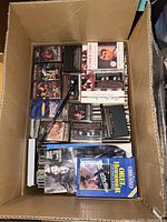 Top view inside one cardboard box showing assorted cassette tapes and vinyl record covers.
