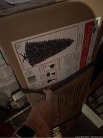 Boxes containing a 7ft pre-lit artificial Christmas tree by Celebrate It brand, shown with product image and label on packaging.