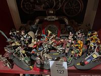 Overview of all four resin biker figurines on a red surface