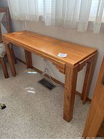 Console table shown from side angle displaying wood grain and leg design.