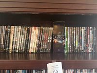 First shelf with assorted DVDs including titles such as 'The Happening,' 'Predator' series, and TV show collections