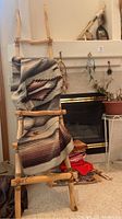 Wooden ladder with leather cord and woven blanket draped over it.
