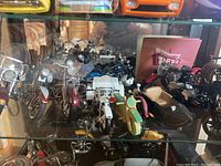 Seven scale model motorcycles on a glass shelf, various colors and sidecars evident