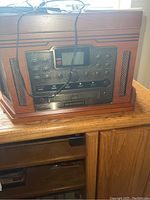 Front view of wood grain Crosley radio with control buttons, display screen, CD recorder slot and speaker grills