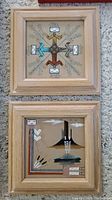 Two square framed sand art pictures with natural wood frames showing geometric and stylized nature designs