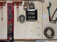 Photo showing various hand tools hanging on pegboard including rolls of tape, a clock, and a metal rod.