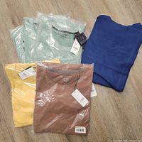 Lot of six folded men's shirts in packaging or tagged, showing colors and textures.