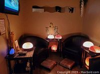 Therapy room setup with 2 black leather armchairs, side tables with various Himalayan salt lamps, decorative plants, and wall art