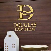 Gold Douglas Law Firm logo mounted on wood panel