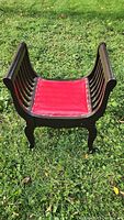 Front view of the antique wooden throne chair with red leather seat on grass.