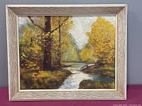 Oil painting in wood frame showing landscape with river and autumn trees