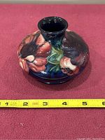 Top and side view showing colorful floral design on dark blue background with visible small repair near rim.