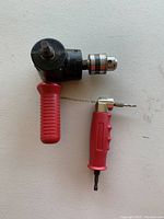 Photo of two 90 degree drills on white surface, showing red ergonomic handles, one labeled Craftsman Drill 90.