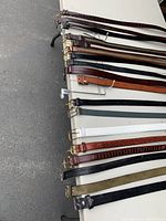 Overview photo of assorted belts laid side by side showing variety in colors and buckle styles.