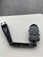 Full view of Audubo BirdCam attached to an adjustable black mounting arm with knobs and bolts for positioning.