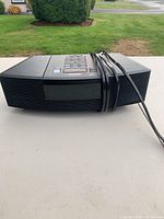 Front side view of compact Bose Wave Radio/CD player showing speaker grille and attached power cord