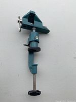 Blue metal C clamp with an attached vice on top from an angled front view, showing the screw handle and vice jaws.