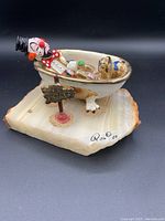 Clown figurine in bathtub on polished stone base with coins and 'NO VACANCY' sign