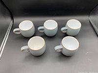 Top down view of five greyish blue coffee cups showing their round shape and interior color.