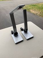 Two Classic brand adjustable desk lamps on a table with power cords wrapped around the arms.