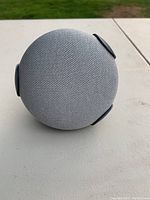 Top view showing round grey fabric speaker with black side clips.