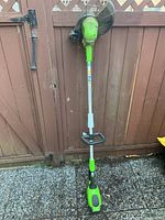 Full view of the Greenworks battery operated weed whacker showing the shaft, handle, and motor head with cutting line.